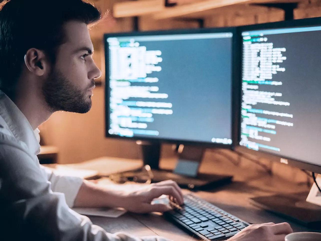 Homme regardant du code sur deux écrans