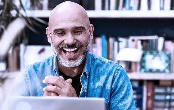 Man Looking At Laptop With Smile