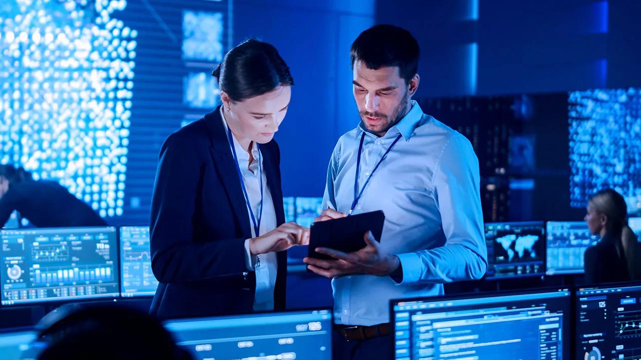 Man and Woman Looking At Tablet in Control Room