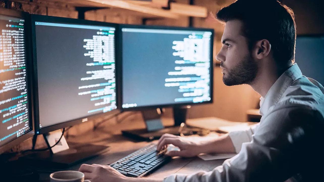 Homme regardant du code sur deux écrans