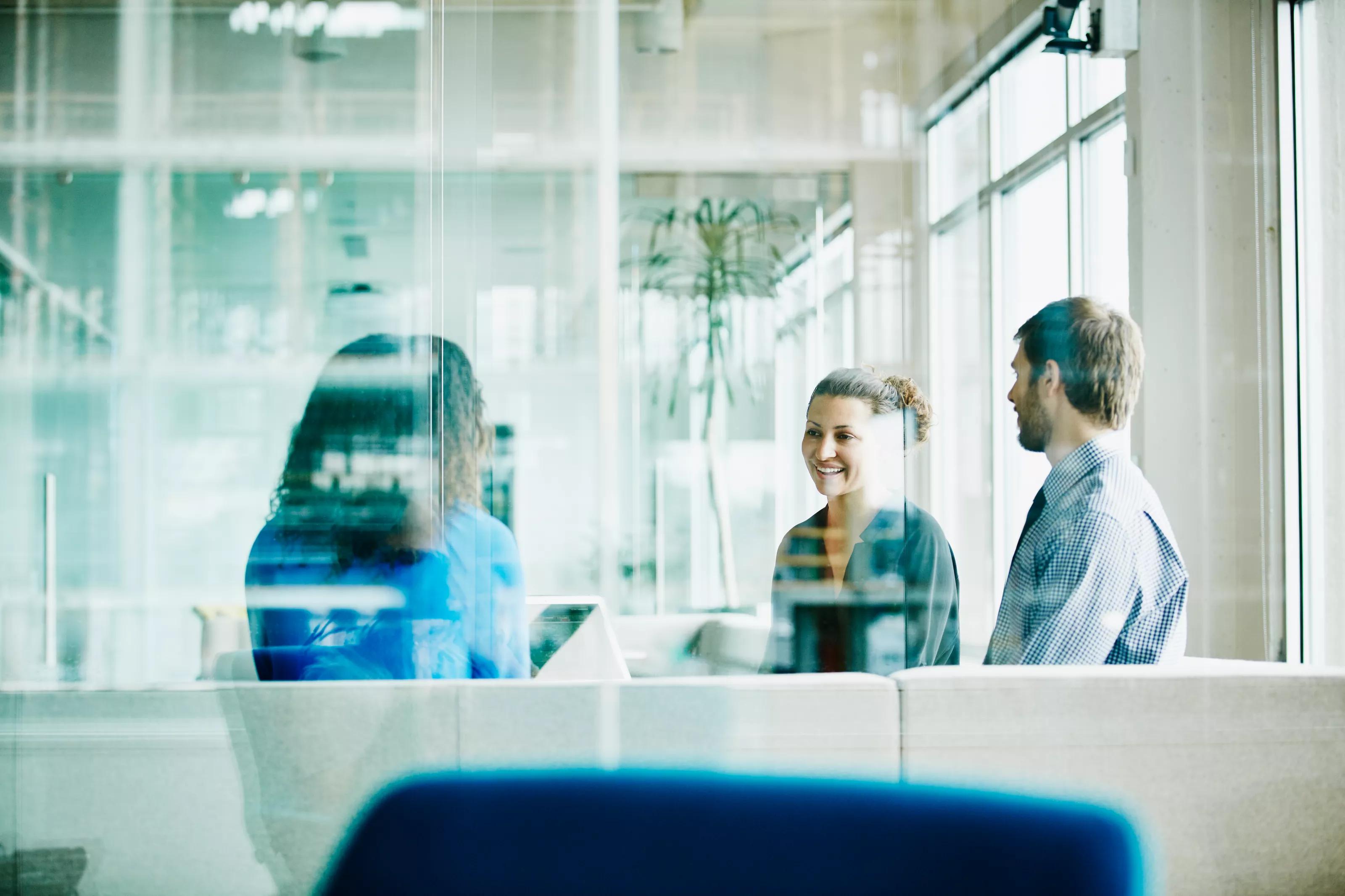 Smiling businesswoman leading team meeting with colleagues in office conference room