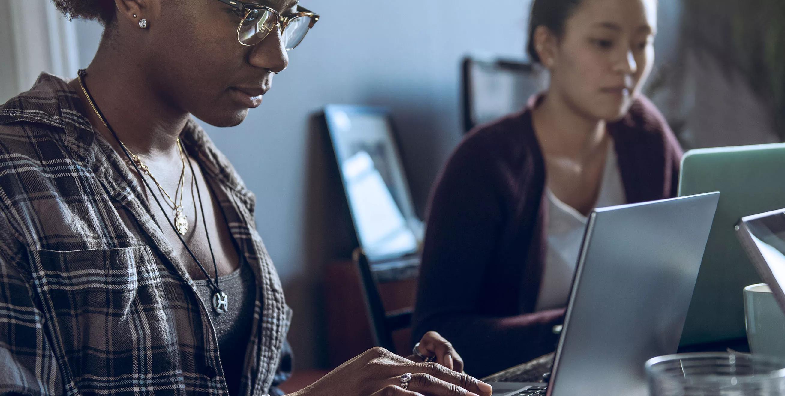 Two Women Working on Laptops in Office