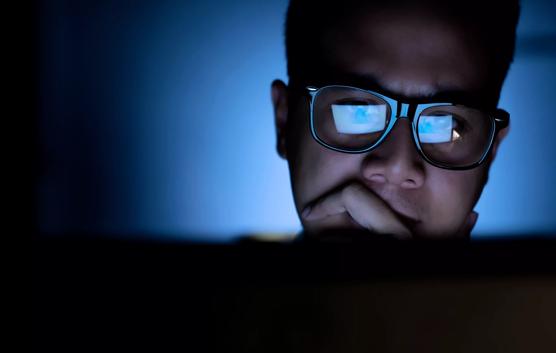 A focused and serious looking man working and thinking hard on a computer