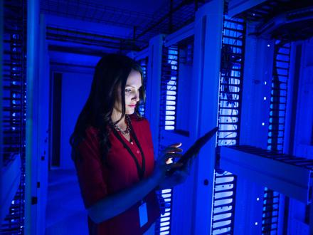 Woman Looks At A Tablet In Server Room