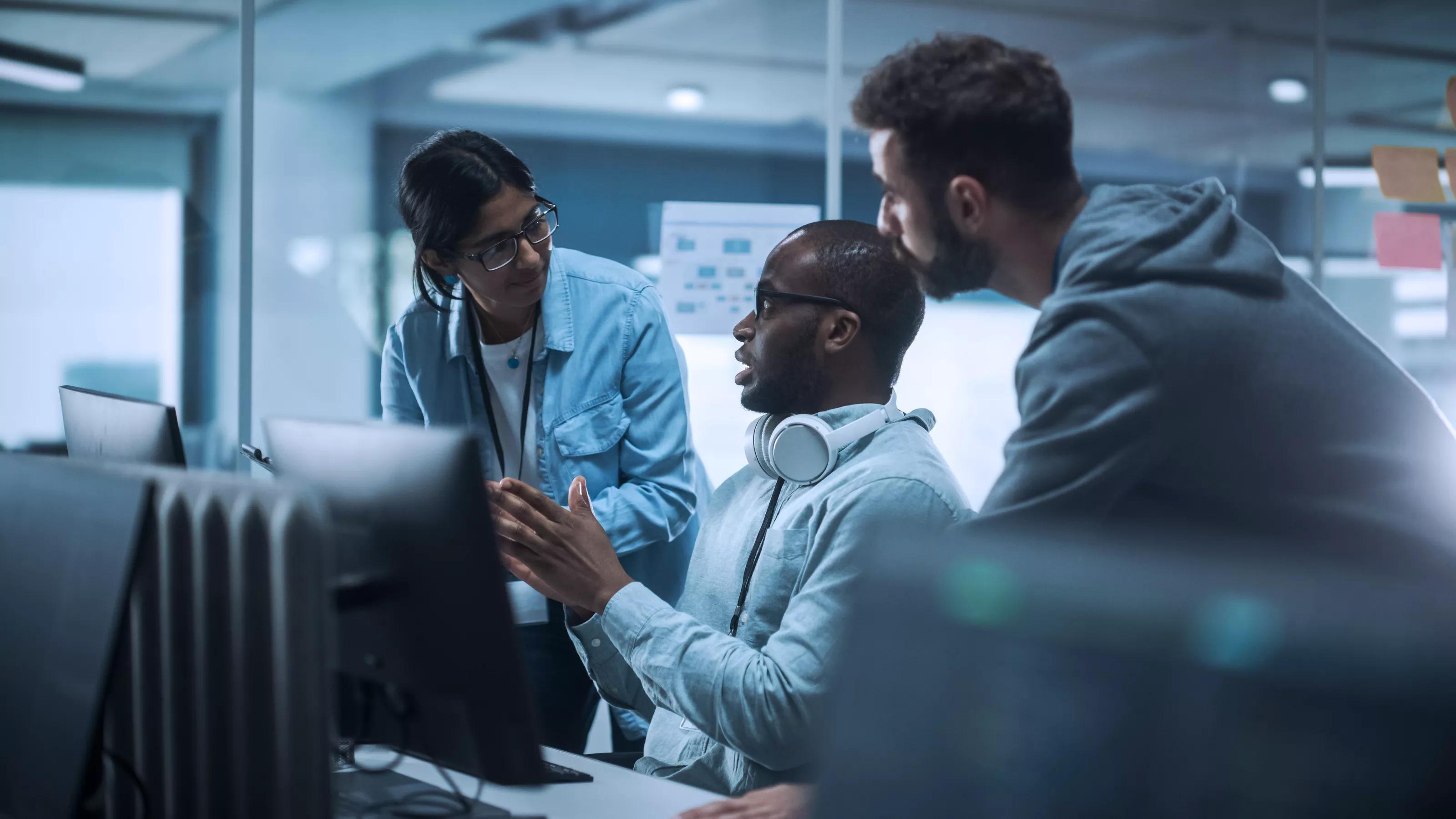 Diverse Group of Professionals Meeting in Modern Office: Energetic and Enthusiastic IT Programmers Use Computer Together, Talk Strategy, Discuss Planning. Software Engineers Develop Inspirational App