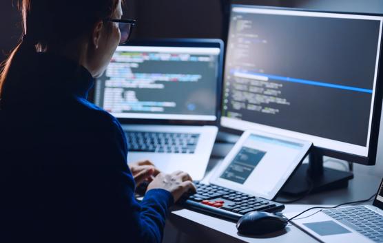 Young Asian woman, developer programmer, software engineer, IT support, wearing glasses working hard at nitght overtime on computer to check coding in bugging system. Back view