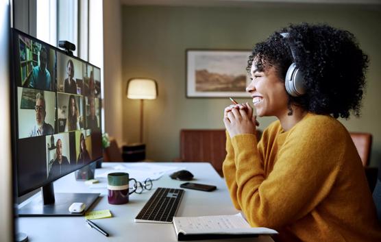 Businesswoman with headphones smiling during video conference. Multiracial male and female professionals are attending online meeting. They are discussing business strategy.