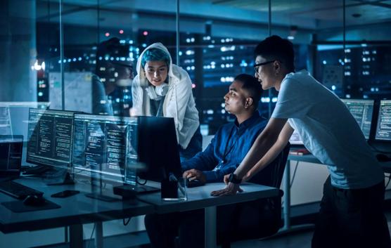 Diverse Team of Professionals Meeting in Office at Night: Brainstorming IT Programmers Use Computer Together, Talk Strategy, Discuss Planning. Software Engineers Develop Inspirational App Program