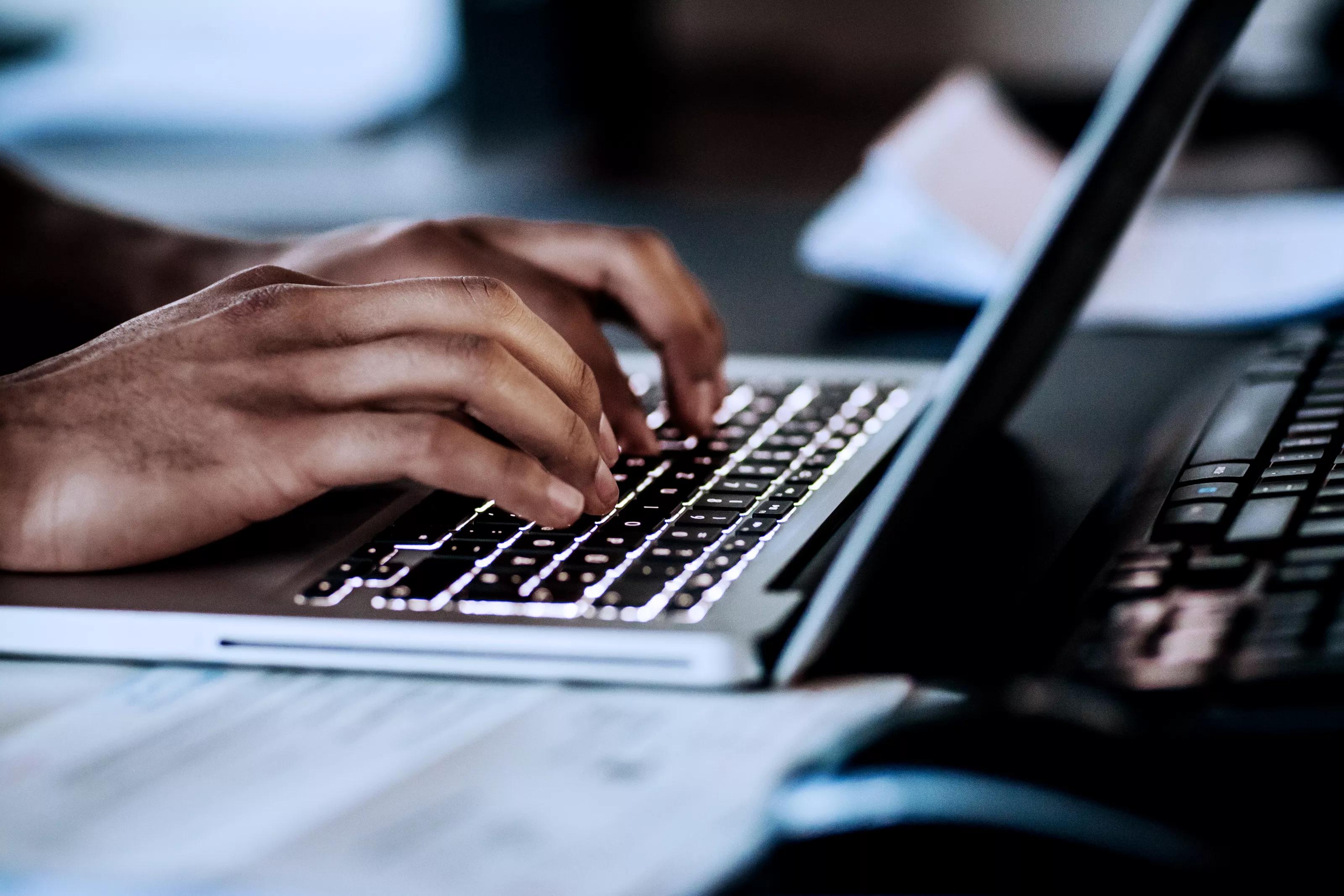 A close up of a man typing on his laptop at the office.