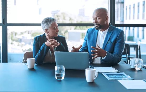 Man and Woman Discussing in Front of Laptop