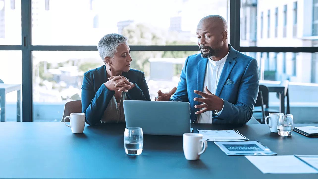 Man and Woman Discussing in Front of Laptop