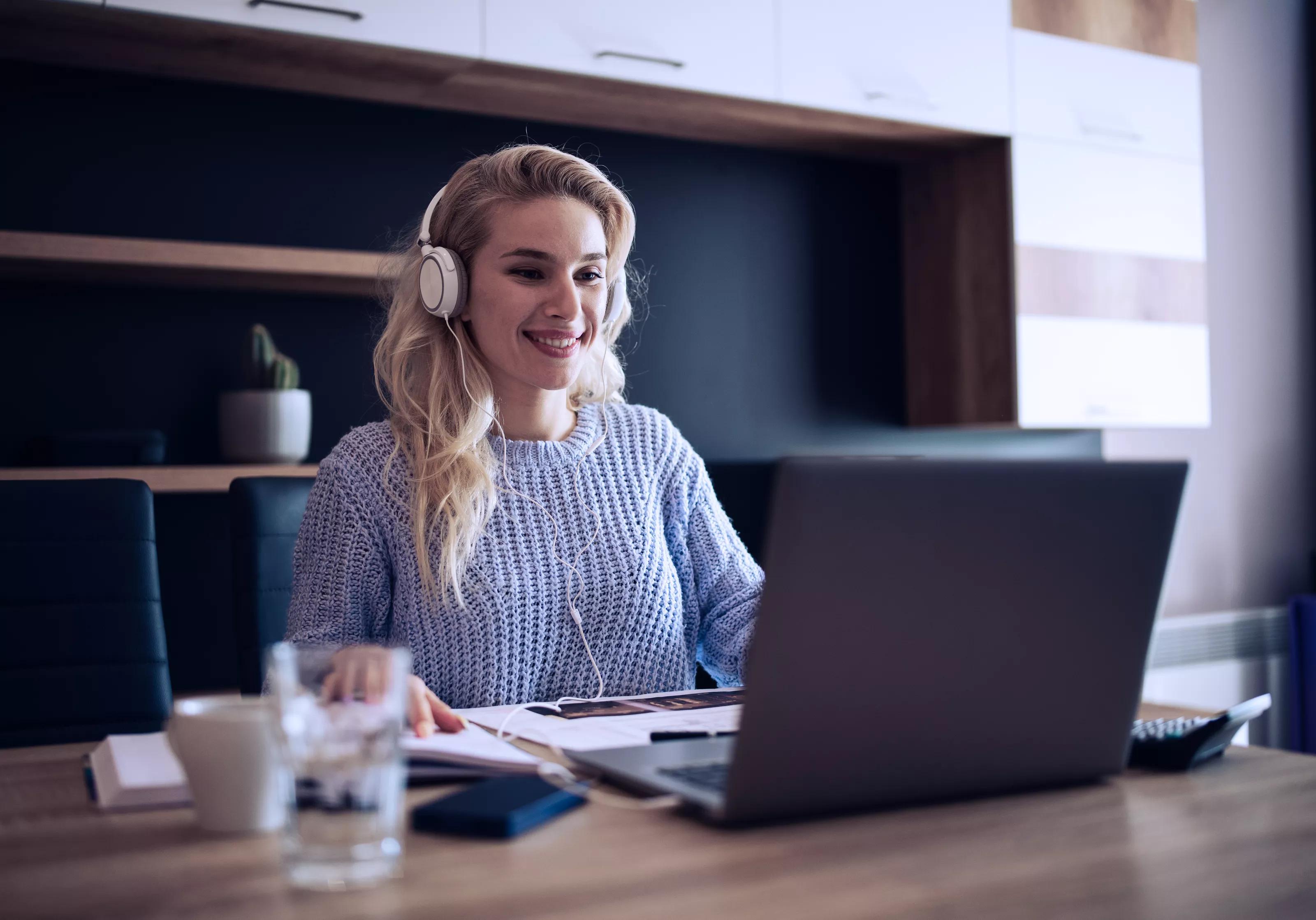 Smiling Woman Listening to Conference Call on Laptop