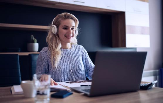Smiling Woman Listening to Conference Call on Laptop