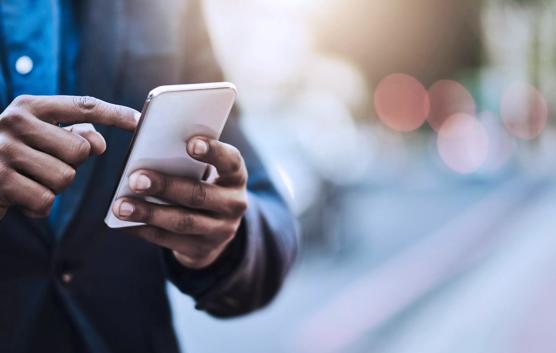 Closeup shot of an unrecognizable businessman using a cellphone in the city