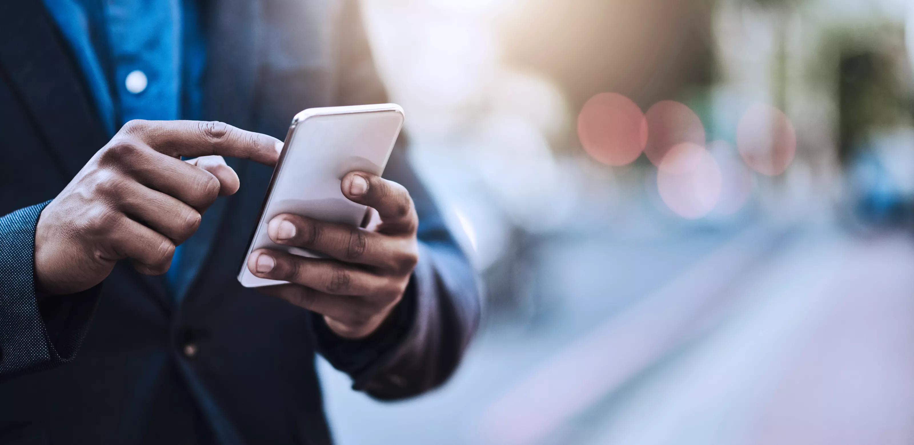 街中でスマートフォンを使用している、とあるビジネスマンのクローズアップ写真